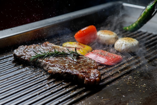 Vista laterale bistecca alla griglia con rosmarino e peperone verde e funghi nel barbecue