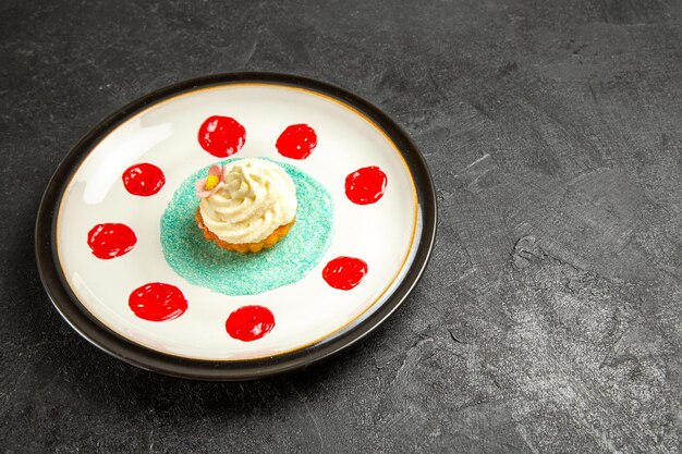 Vista laterale cibo gustoso sul piatto bianco un appetitoso cupcake con salse sulla superficie scura