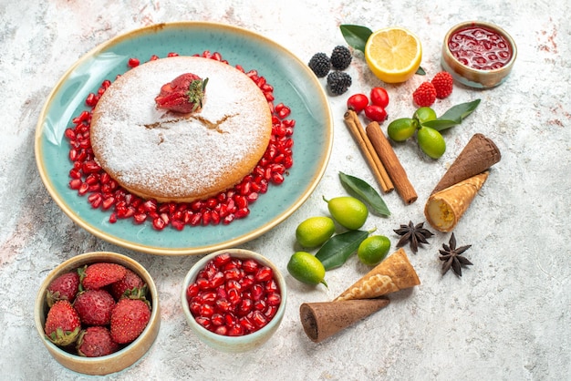 Vista laterale da lontano biscotti e torta una torta marmellata di bacche di melograno limone cannella anice stellato