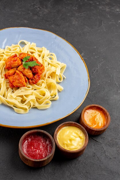 Vista laterale da lontano pasta e salse piatto di sugo di pasta e carne appetitosa e salse colorate sul tavolo