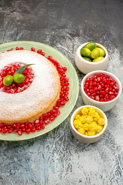 Vista laterale da lontano torta e dolci semi di melograno agrumi caramelle una torta appetitosa