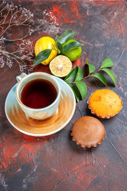 Vista laterale da lontano una tazza di tè una tazza di tè gli appetitosi agrumi con foglie cupcakes