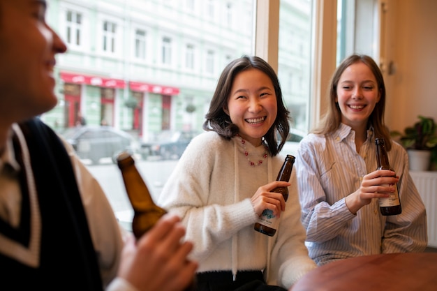 Vista laterale degli amici sorridenti con il kombucha