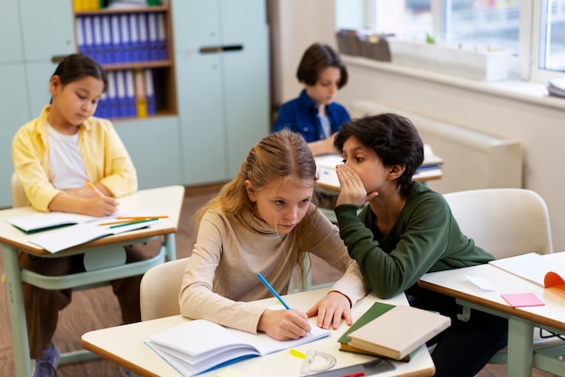 Vista laterale dei bambini che tradiscono a scuola