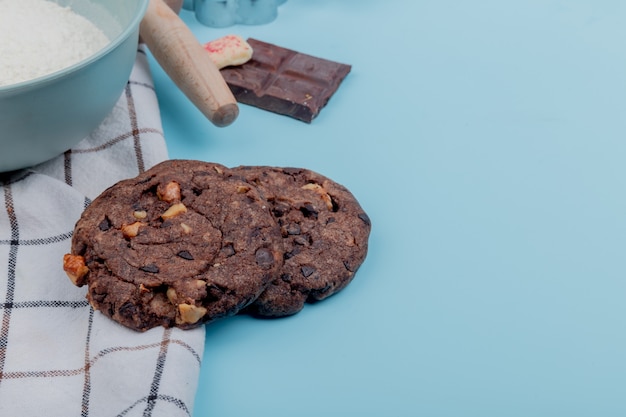 Vista laterale dei biscotti con il cioccolato della farina sulla superficie del blu con lo spazio della copia