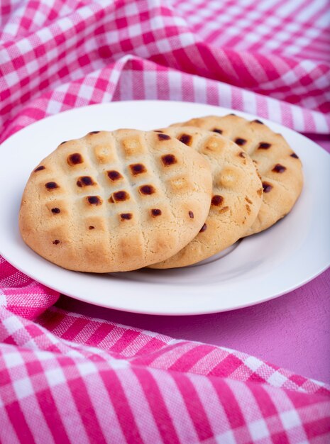 Vista laterale dei biscotti su un piatto bianco sul rosa