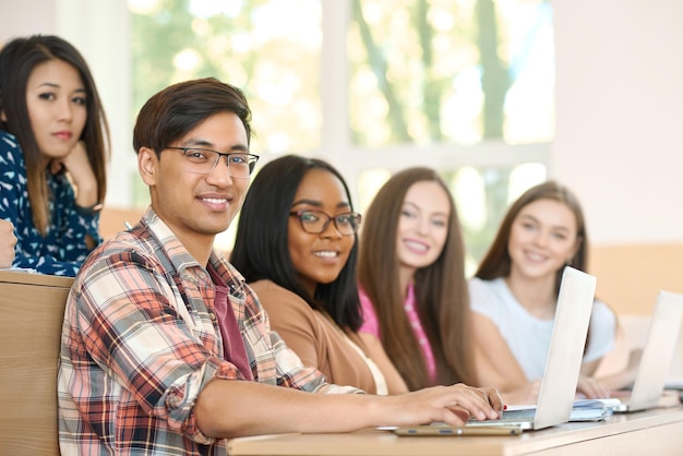 Vista laterale dei compagni di gruppo che guardano la telecamera seduti all'università