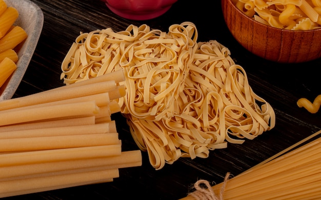 Vista laterale dei maccheroni come tagliatelle bucatini fusilli e altri sulla tavola di legno