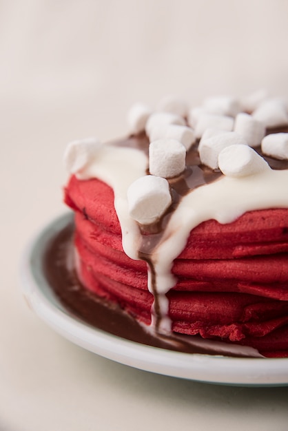 Vista laterale dei pancake rossi con crema e caramelle gommosa e molle in zolla