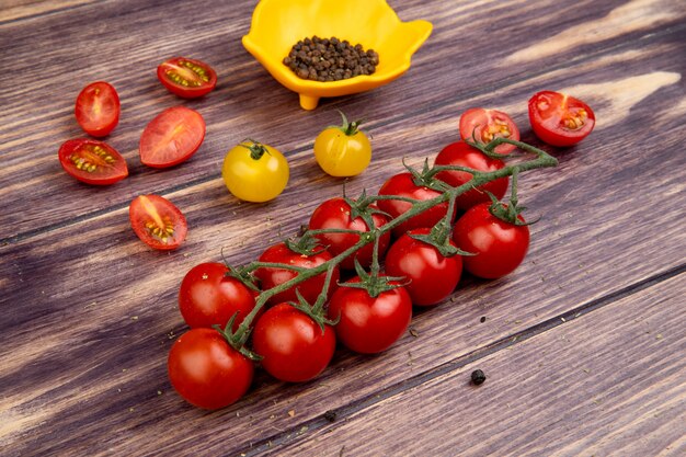 Vista laterale dei pomodori con i semi del pepe nero sulla tavola di legno