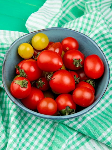 Vista laterale dei pomodori in ciotola sul panno su superficie verde