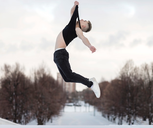 Vista laterale del ballerino maschio che posa mentre nell'aria