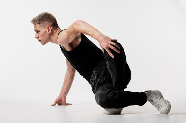 Vista laterale del ballerino maschio in jeans e scarpe da ginnastica che posano mentre ballano