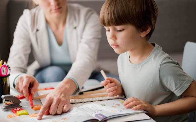 Vista laterale del bambino che impara dal tutor a casa