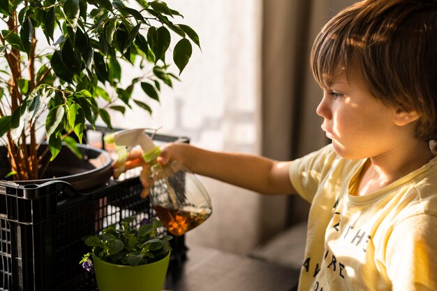 Vista laterale del bambino che innaffia le piante