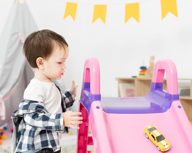 Vista laterale del bambino con il giocattolo e lo scorrevole