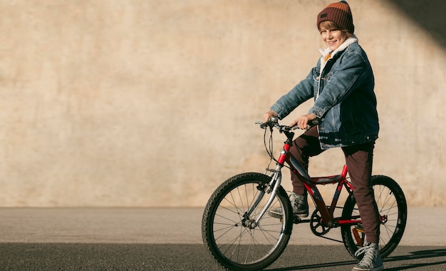 Vista laterale del bambino in bicicletta all'aperto con copia spazio