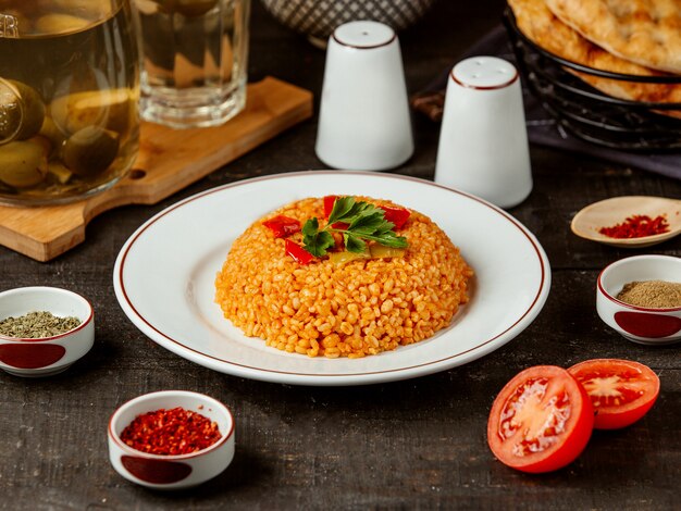 Vista laterale del bulgur turco di cucina con le verdure sul piatto