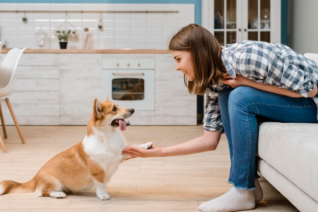 Vista laterale del cane che dà zampa al proprietario