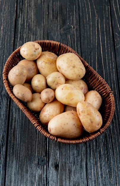 Vista laterale del canestro con le patate su fondo di legno con lo spazio della copia