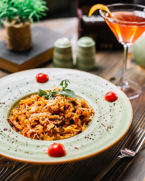 Vista laterale del cocktail sumakh della menta del pomodoro parmigiano del fungo del pollo della pasta di Fettuccine