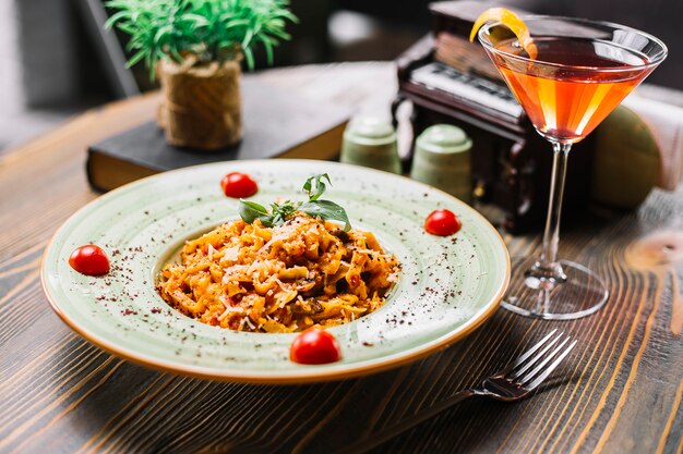 Vista laterale del cocktail sumakh della menta del pomodoro parmigiano del fungo del pollo della pasta di Fettuccine