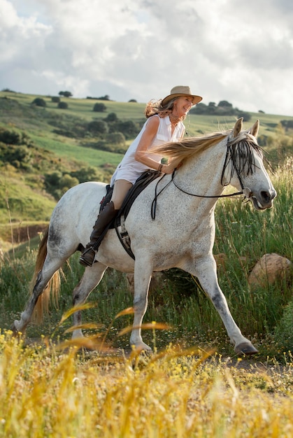 Vista laterale del contadino femminile a cavallo nella natura