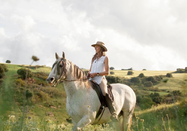 Vista laterale del contadino femminile a cavallo nella natura