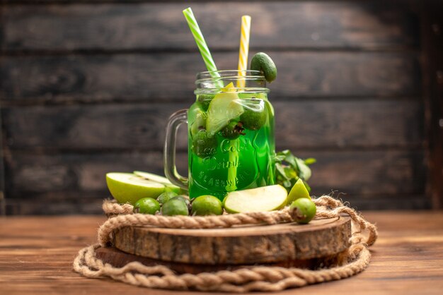 Vista laterale del delizioso succo di frutta fresco servito con mela e feijoas su un tagliere di legno