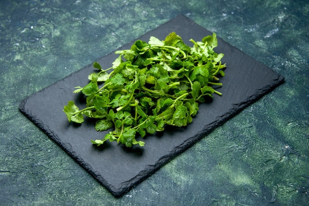 Vista laterale del fascio di coriandolo sul tagliere di legno su sfondo verde nero colori misti con spazio libero