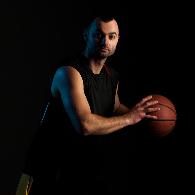 Vista laterale del giocatore di pallacanestro che posa con la palla