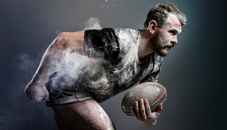 Foto gratuito vista laterale del giocatore di rugby maschile atletico che tiene palla con polvere