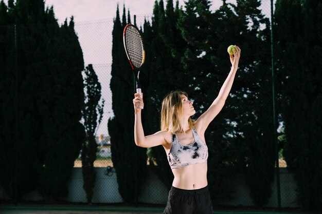 Vista laterale del giocatore di tennis femminile che serve