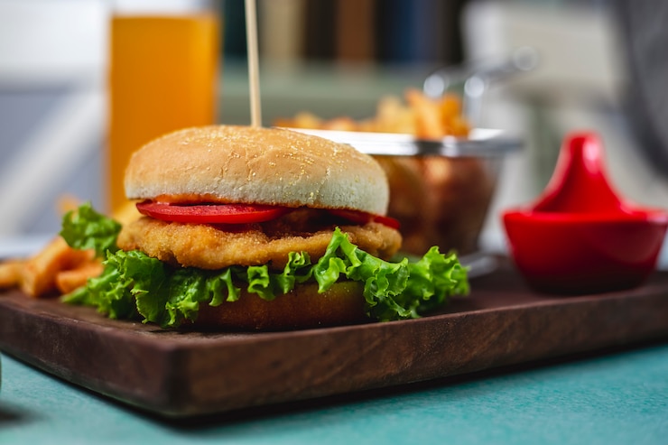 Foto gratuito vista laterale del ketchup delle patate fritte del formaggio del pomodoro della lattuga dell'hamburger del pollo