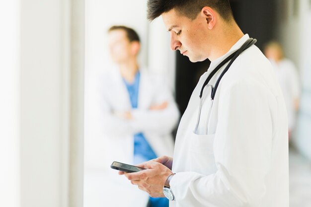 Vista laterale del medico con lo smartphone