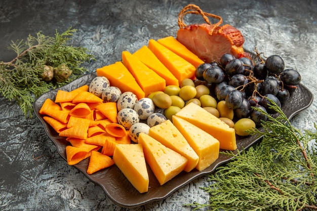 Vista laterale del miglior spuntino delizioso per il vino su vassoio marrone e rami di abete su sfondo di ghiaccio