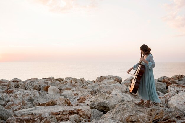 Vista laterale del musicista femminile che suona il violoncello