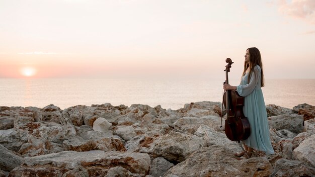 Vista laterale del musicista femminile con il violoncello