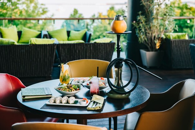 Vista laterale del narghilé dei cocktail delle insalate dei rotoli di sushi dell'insieme di cena