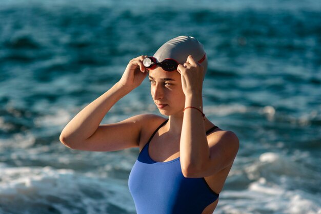 Vista laterale del nuotatore femminile con cappuccio e occhiali da nuoto