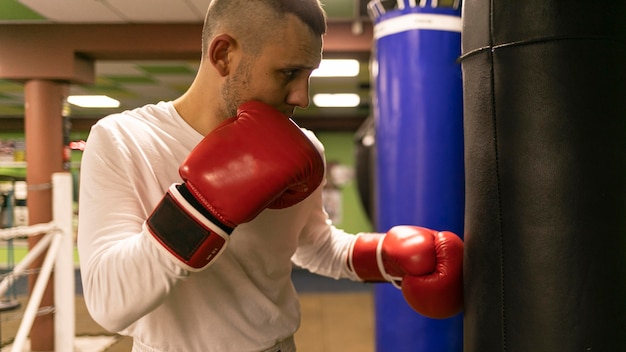 Vista laterale del pugile maschio che pratica con il sacco da boxe