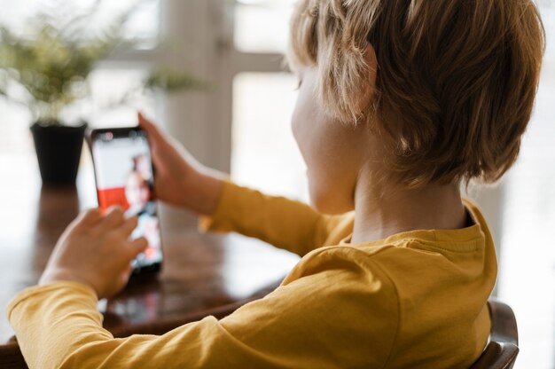 Vista laterale del ragazzo utilizza lo smartphone a casa