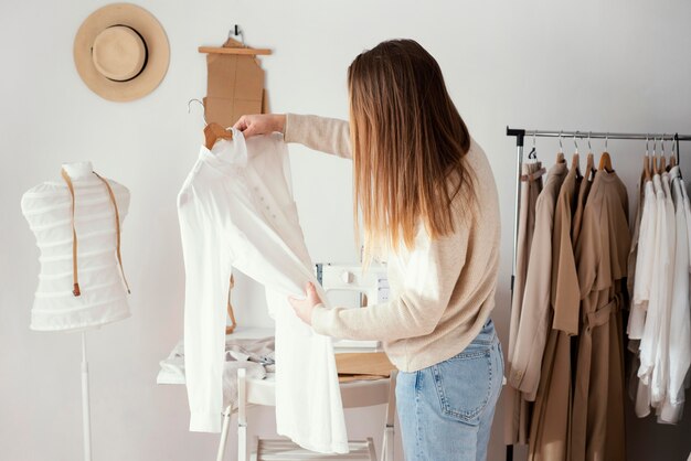 Vista laterale del sarto femminile che controlla gli indumenti