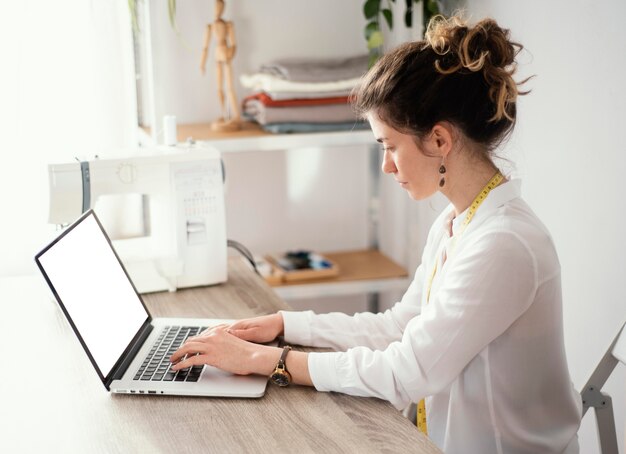 Vista laterale del sarto femminile con laptop