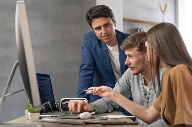 Vista laterale del team di professionisti che lavorano con le nuove tecnologie su computer e laptop