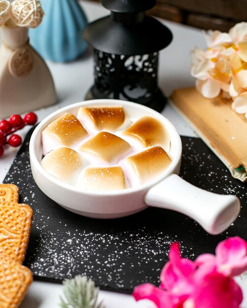 Vista laterale del tradizionale piatto del Ringraziamento casseruola di patate dolci con marshmallow in porzioni su un tagliere di legno nero