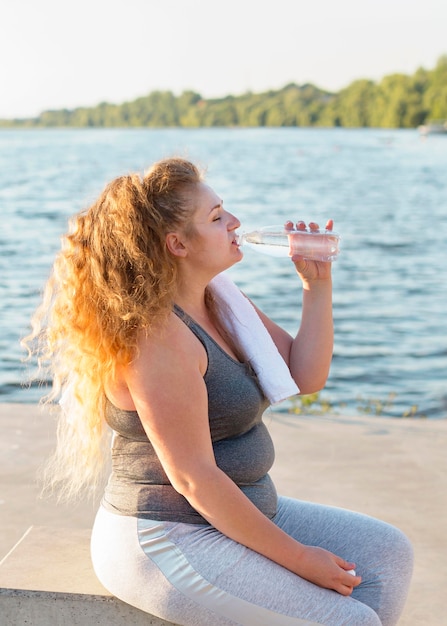 Vista laterale dell'acqua potabile della donna dopo aver lavorato in riva al lago