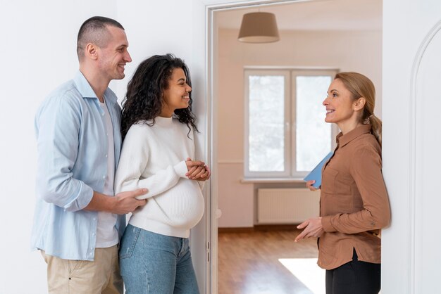 Vista laterale dell'agente immobiliare che invita le coppie a vedere la nuova casa