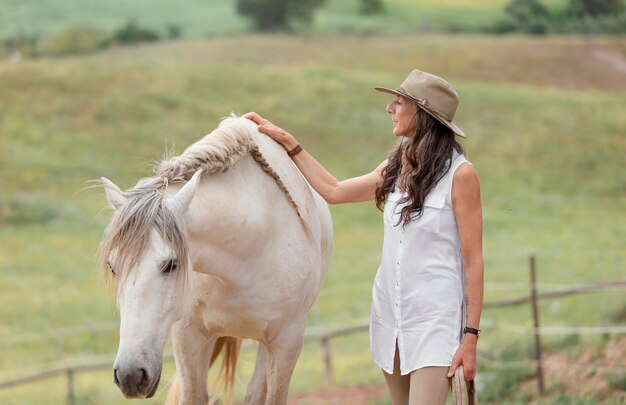 Vista laterale dell'agricoltore femminile che accarezza il suo cavallo