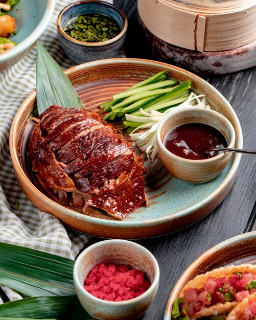 Vista laterale dell'anatra di Pechino asiatica tradizionale dell'alimento con i cetrioli e la salsa su un piatto